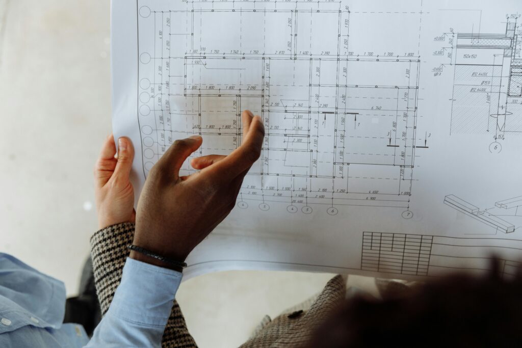 In-depth view of hands examining a detailed architectural blueprint with precise measurements.